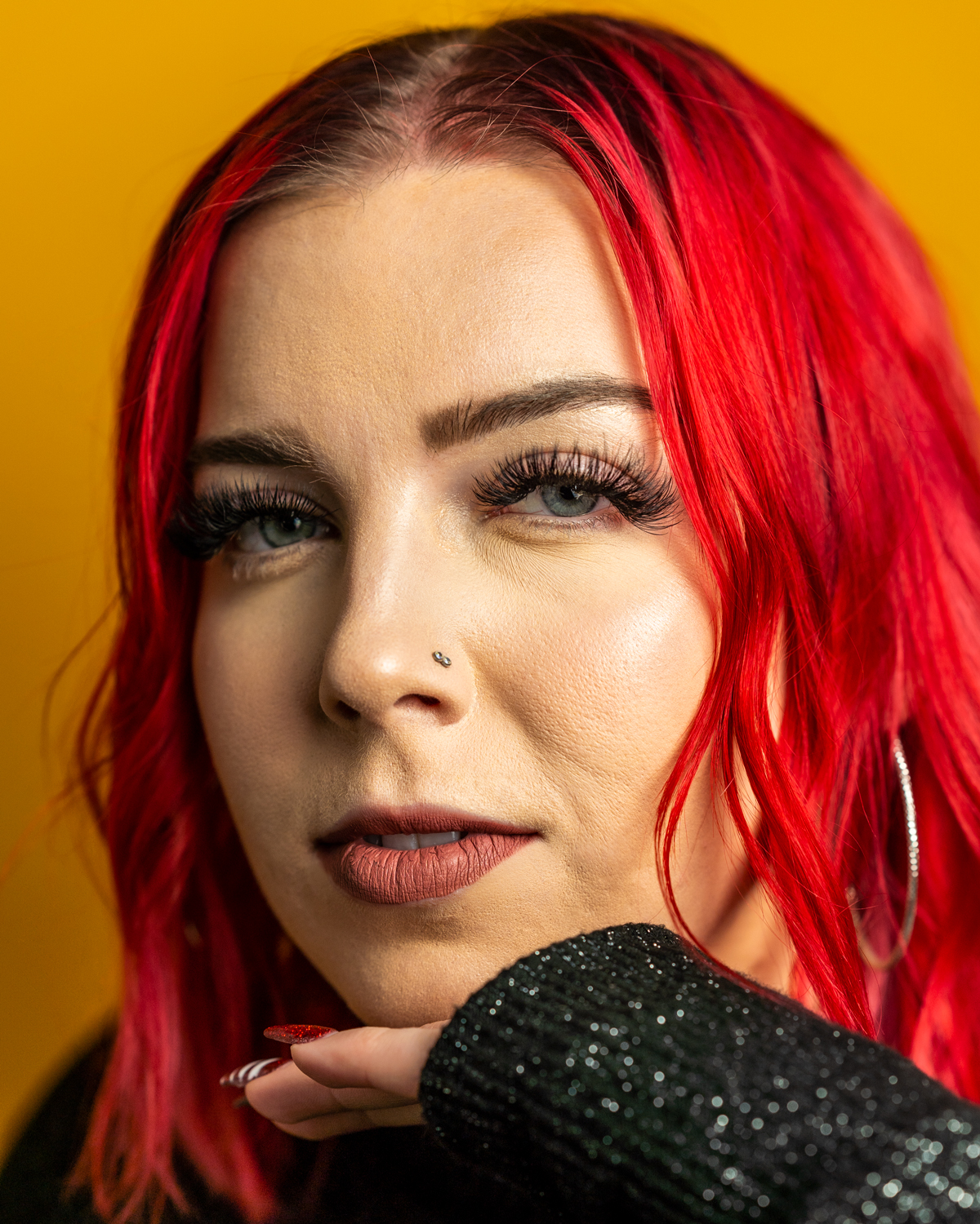 Portrait of Carly Schlichtman with red hair against yellow background.